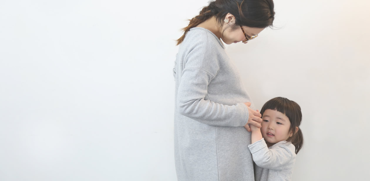 夫婦でおなかの赤ちゃんへ微笑むマタニティフォト